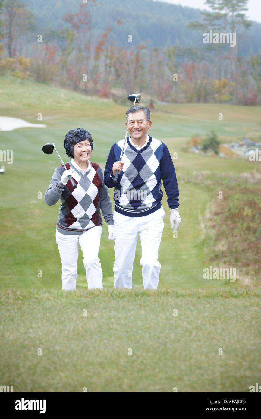 middle aged couple walking on golf field Stock Photo
