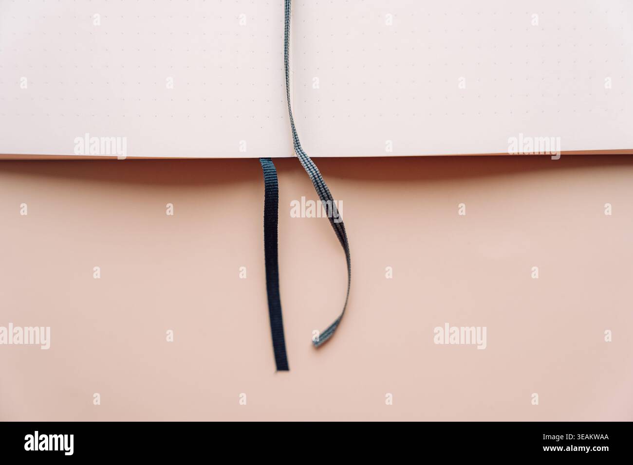 Open dot grid notebook with blue ribbon on beige background Stock Photo