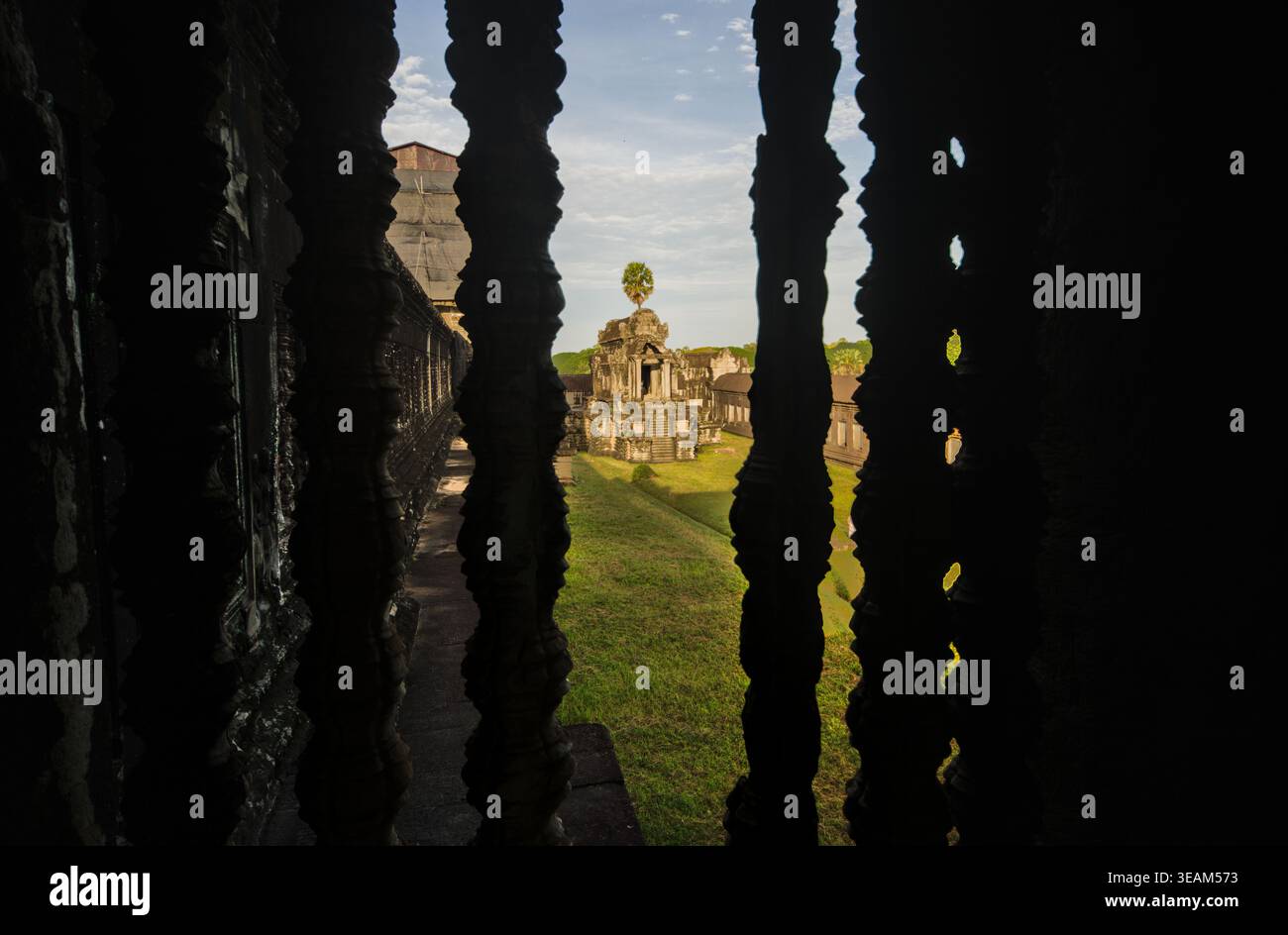 Dark temple interior at Angkor with backlit carved stone balusters ...