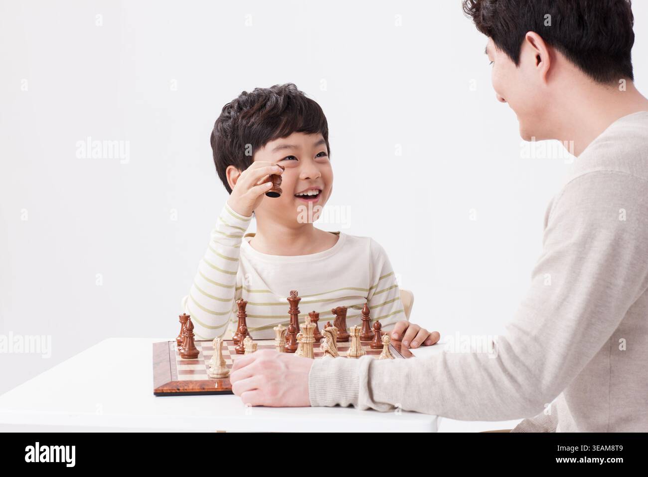 a father and a son playing chess together Stock Photo