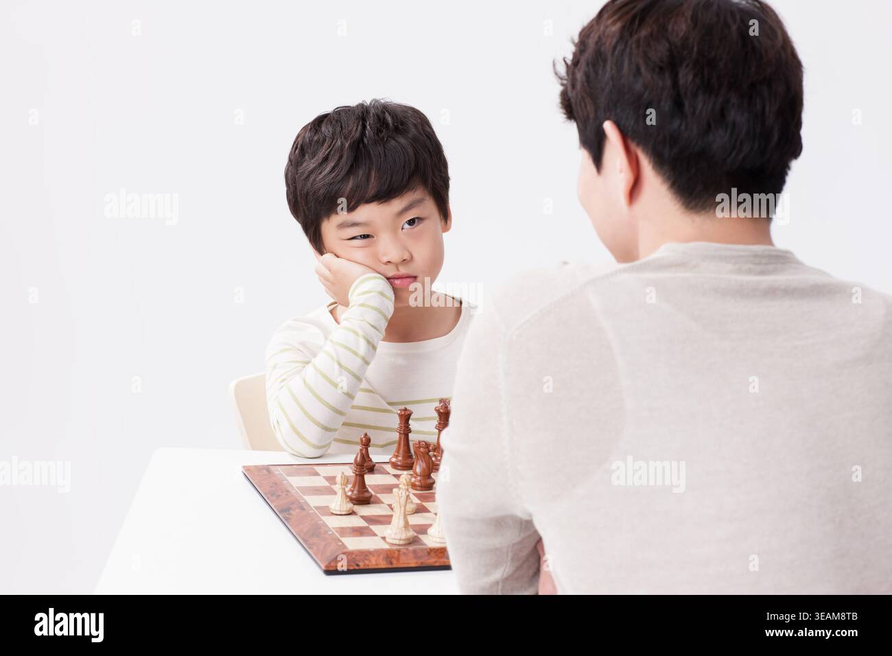 a father and a son playing chess together Stock Photo