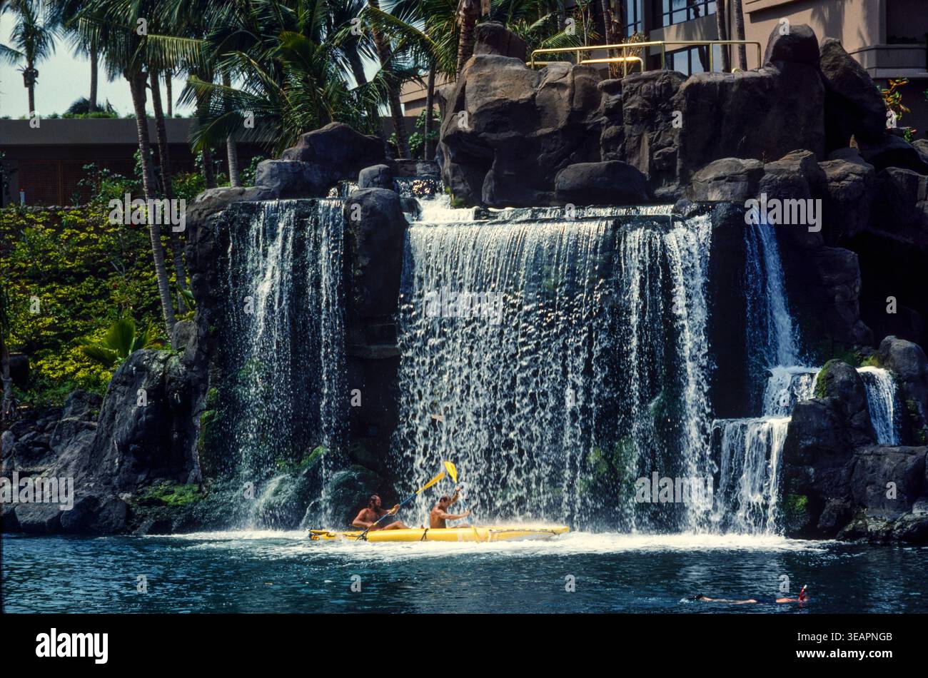 Hoterl guests paddle through an artificial waterfall at an up-market hotel on Maui Island, Hawaii, USA Stock Photo
