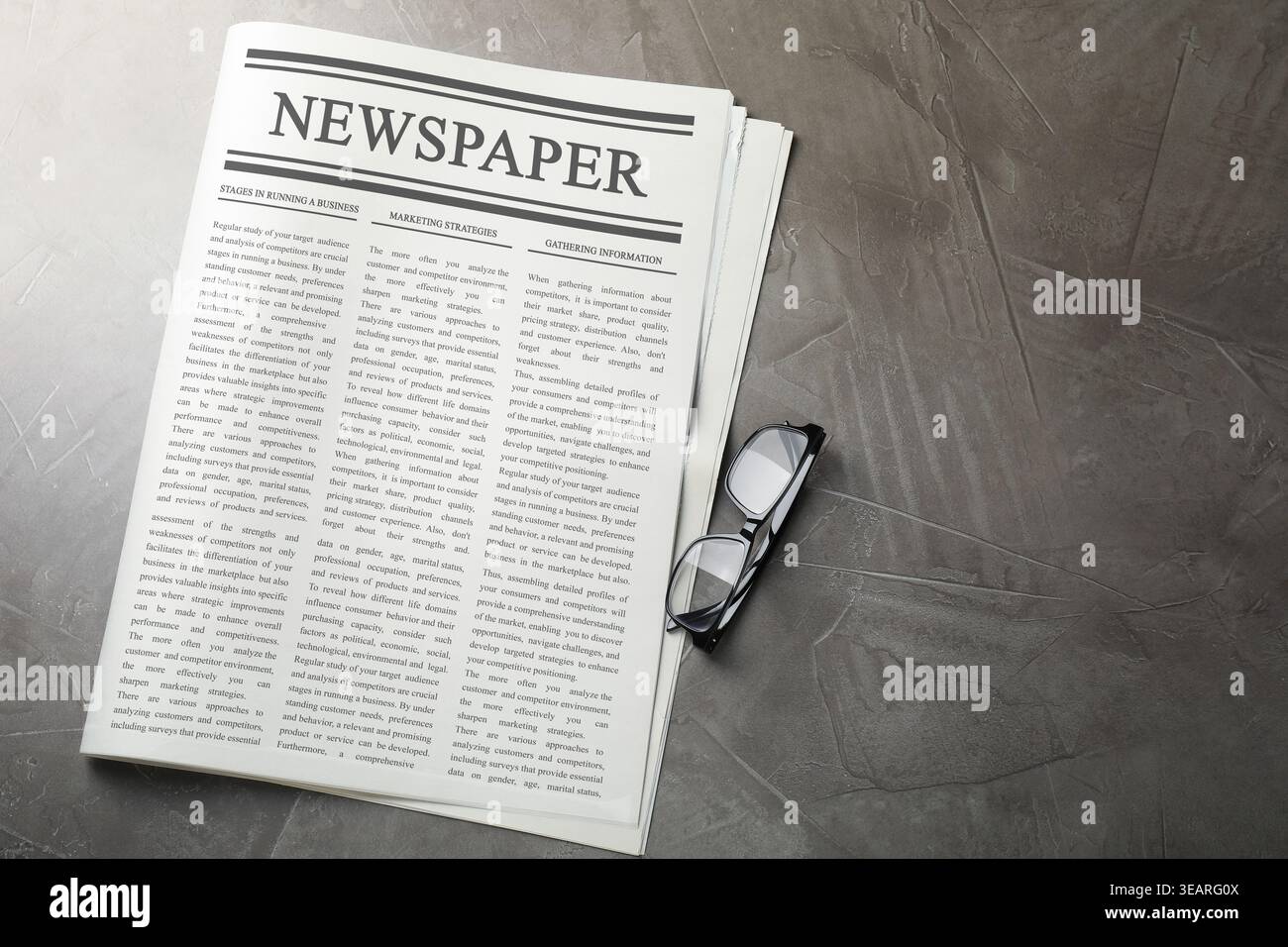 Newspaper and glasses on grey table, flat lay Stock Photo