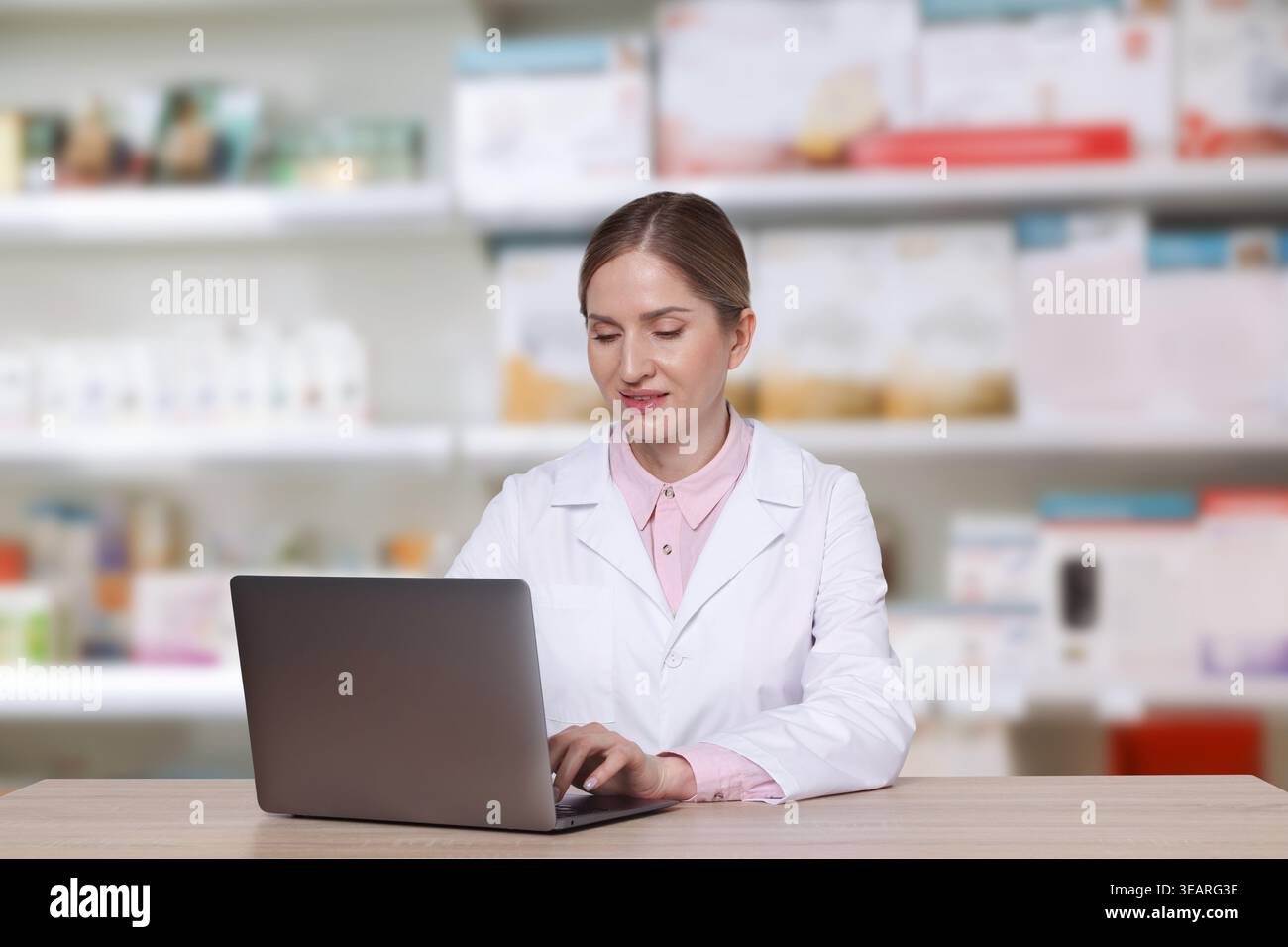 Pharmacist using laptop at table in drugstore Stock Photo