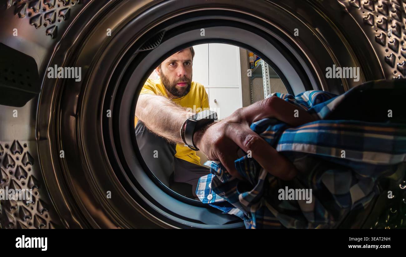 Man loading clothes into washing machine Stock Photo