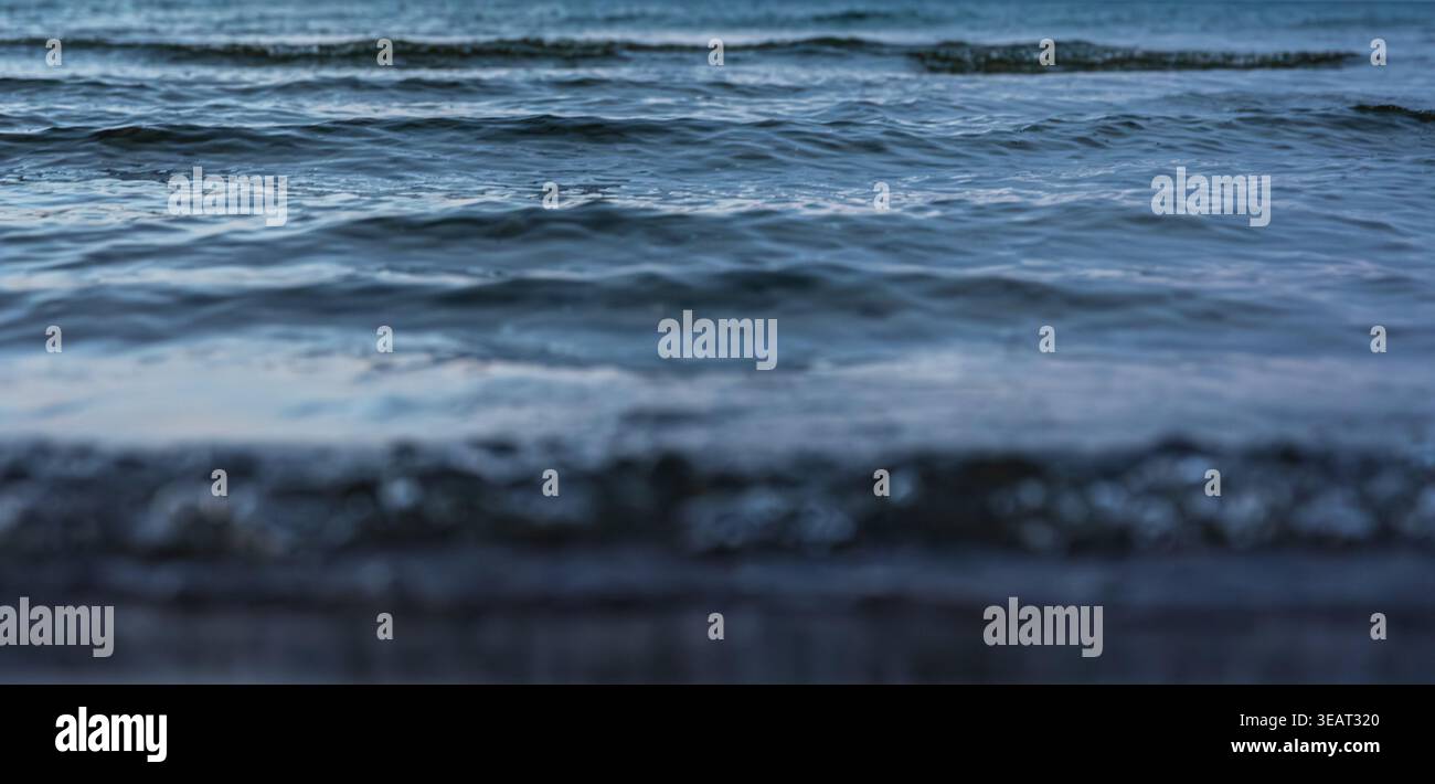Dark sea waves under evening sky. Water texture on the coast at dusk. Stock Photo
