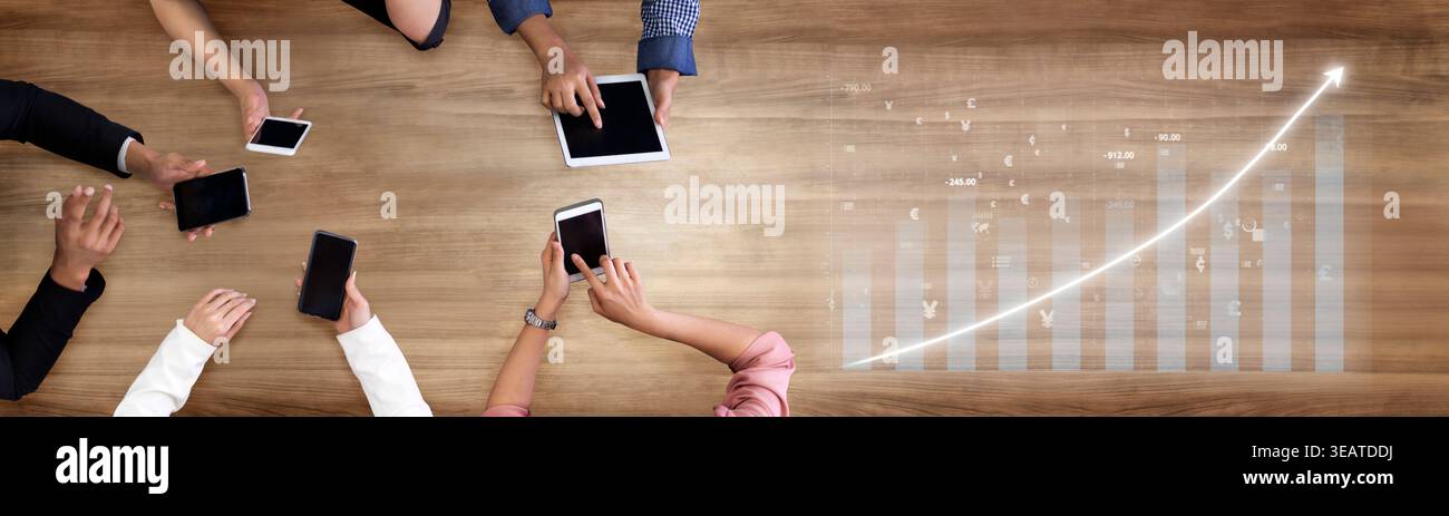 A collaborative workspace showcasing hands interacting with digital devices on a wooden table, representing growth and analysis through data Stock Photo
