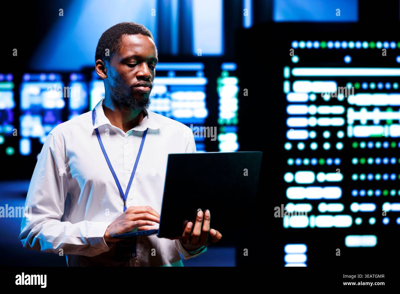 IT programmer in server hub using laptop to find network issues affecting supercomputer performance. Employee fixing issues leading to slow data transfer rates and poor client communication Stock Photo