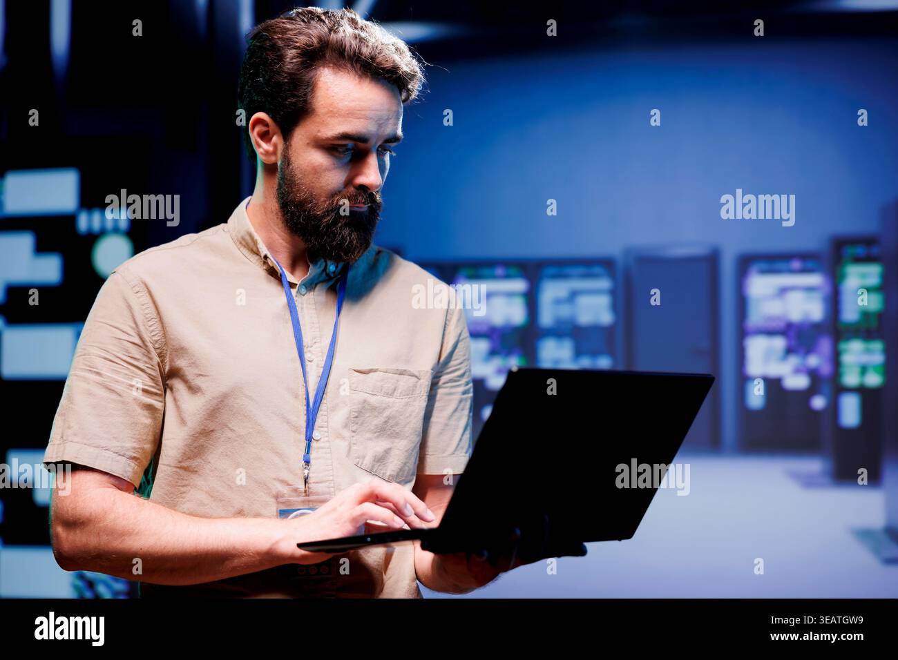 IT admin in hardware room containing server rackmounts, storage devices and networking units providing vast amounts of computing resources. Supervisor doing software maintenance using laptop Stock Photo
