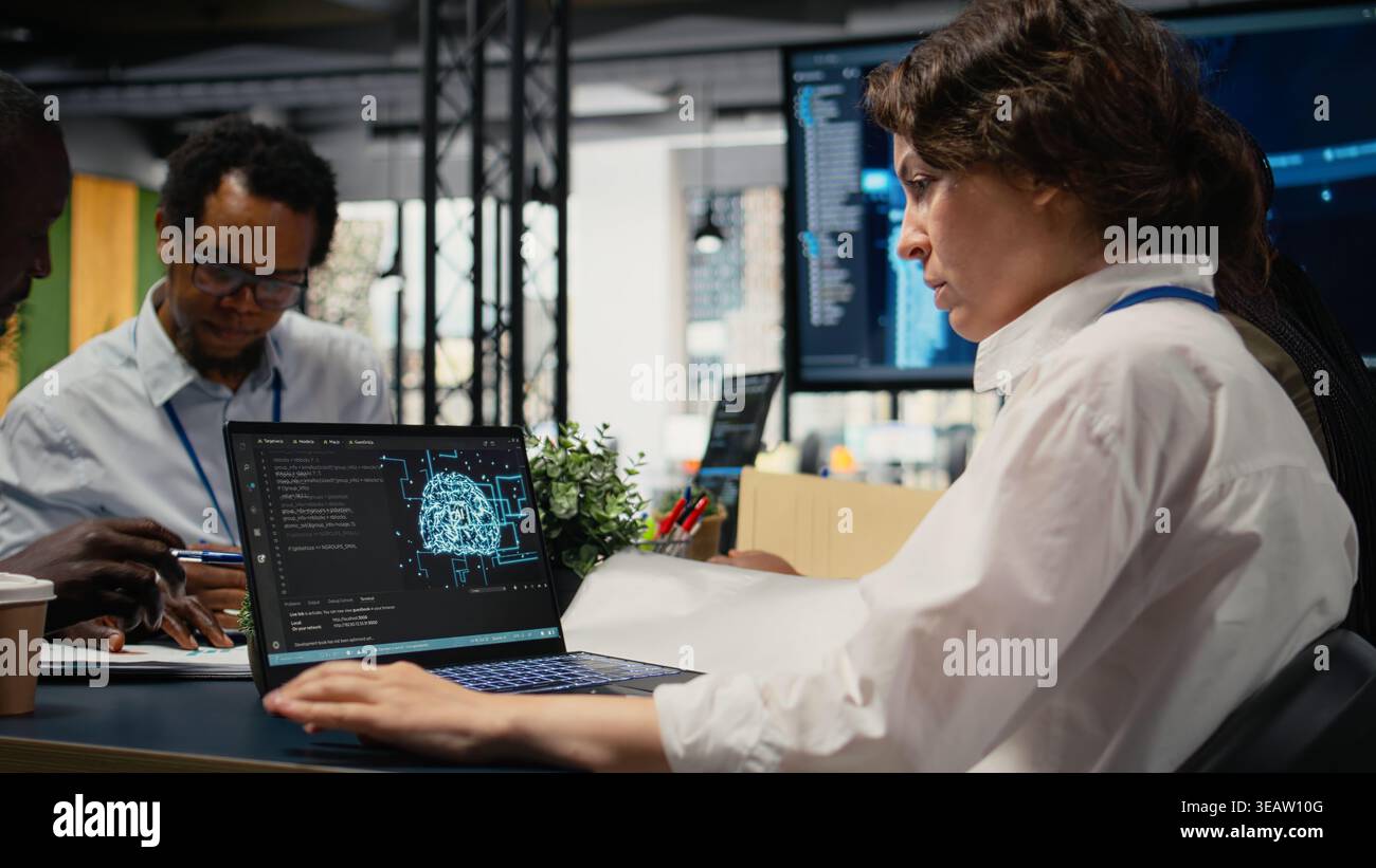 Programmers in office using specialized technology to accelerate complex AI calculations. IT workers managing neural network training datasets with notebook device, camera A Stock Photo