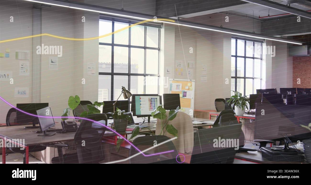 Showing central workstations featuring multiple monitors, chairs and plants in open-plan office Stock Photo