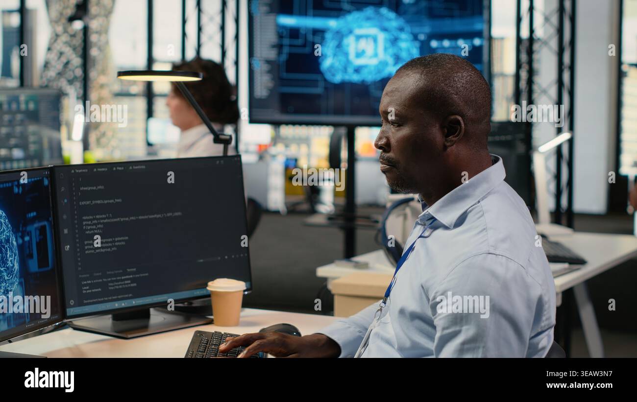 Data scientist in office automating workflows using artificial intelligence on PC. IT professional refines deep learning computational models on computer for faster processing, camera B Stock Photo