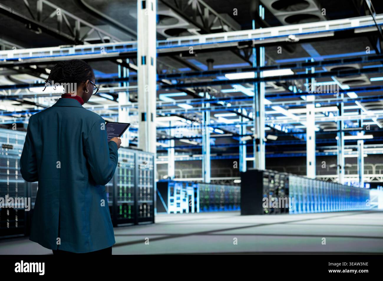 Data center computer scientist coding on tablet, upgrading autonomous IT infrastructure rigs.IT expert walking in server farm, using programming script app on device to update systems Stock Photo