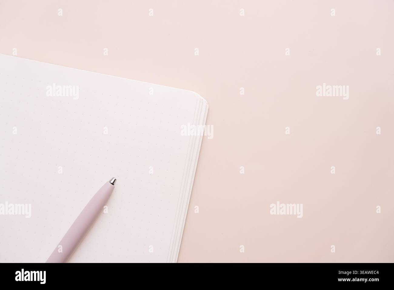Pink pen and notebook on beige background with copy space Stock Photo