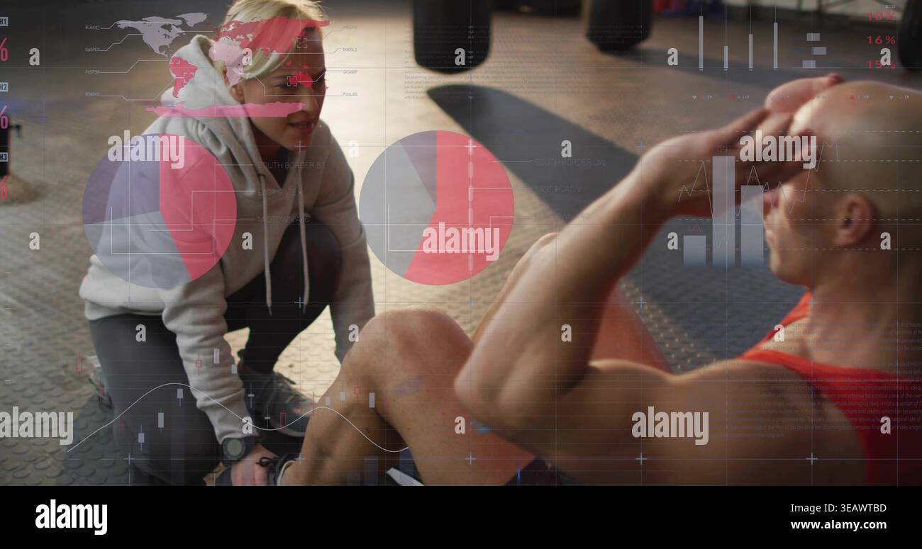 Bracing trainer in hoodie holding feet while male doing situps on mat with data overlays, watch Stock Photo