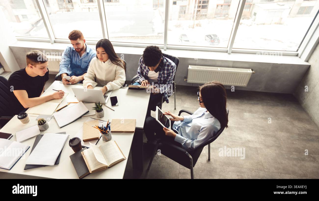 Collaborative Group Working on Laptops and Notebooks in Modern Office Space During Daytime Stock Photo
