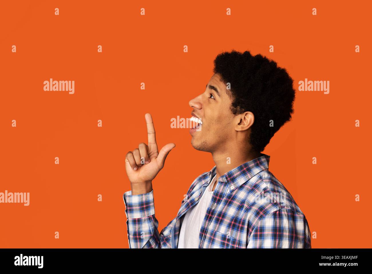 Young Man Expressing Excitement Against a Vibrant Orange Background Stock Photo