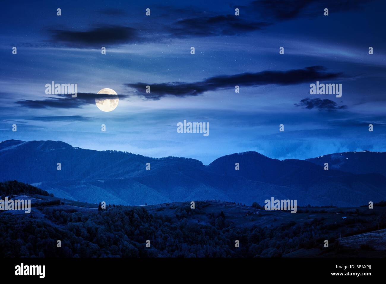 mountainous countryside scenery at night. mysterious sky above the distant valley and ridge. full moon over remote meadows and trees on rolling hills. Stock Photo
