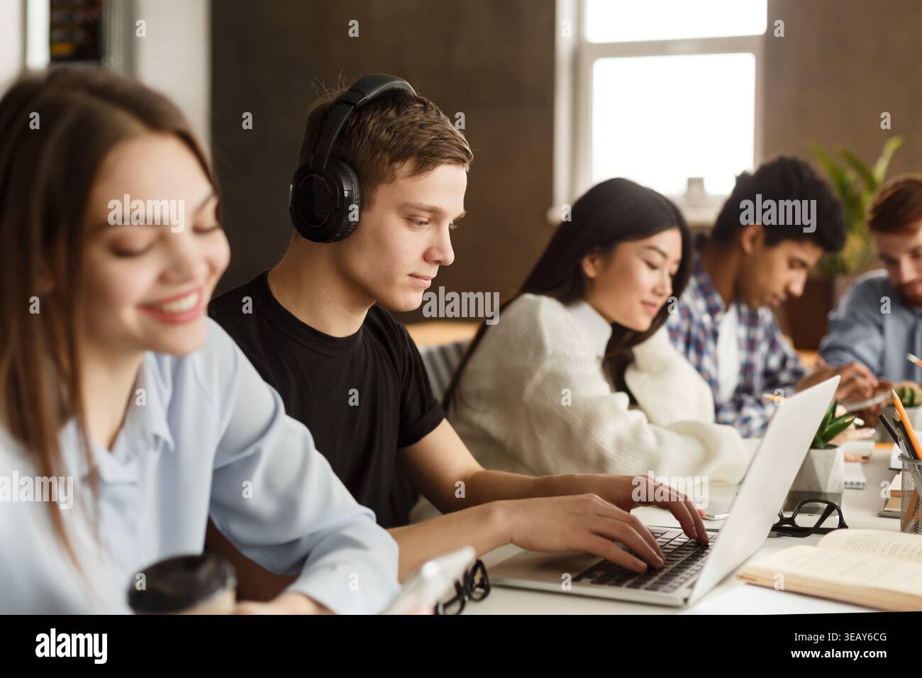 Students Engaged in Study Session at Modern Workspace With Technology and Coffee Stock Photo