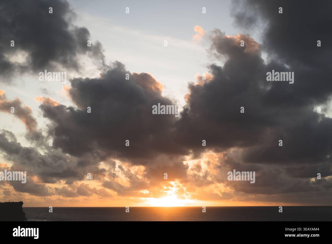 Dramatic sunset with sun breaking through dark storm clouds, Bali Stock Photo