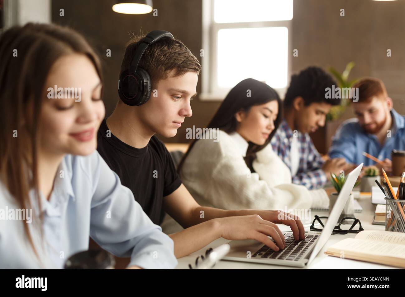 Students Focused on Studies in a Modern Workspace With Laptops and Coffee Cups Stock Photo