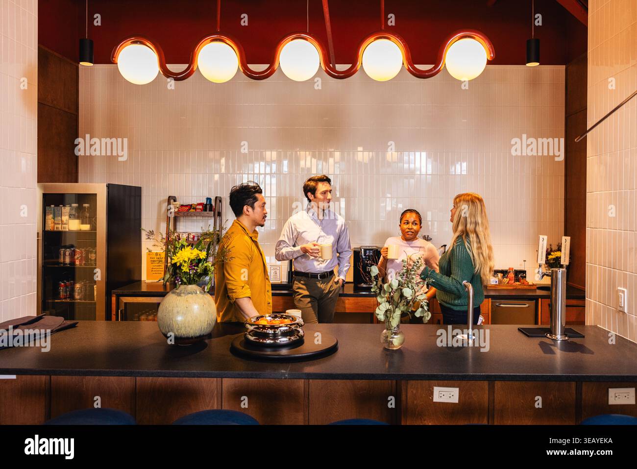 Young Office Team Having a Discussion In Kitchen Stock Photo