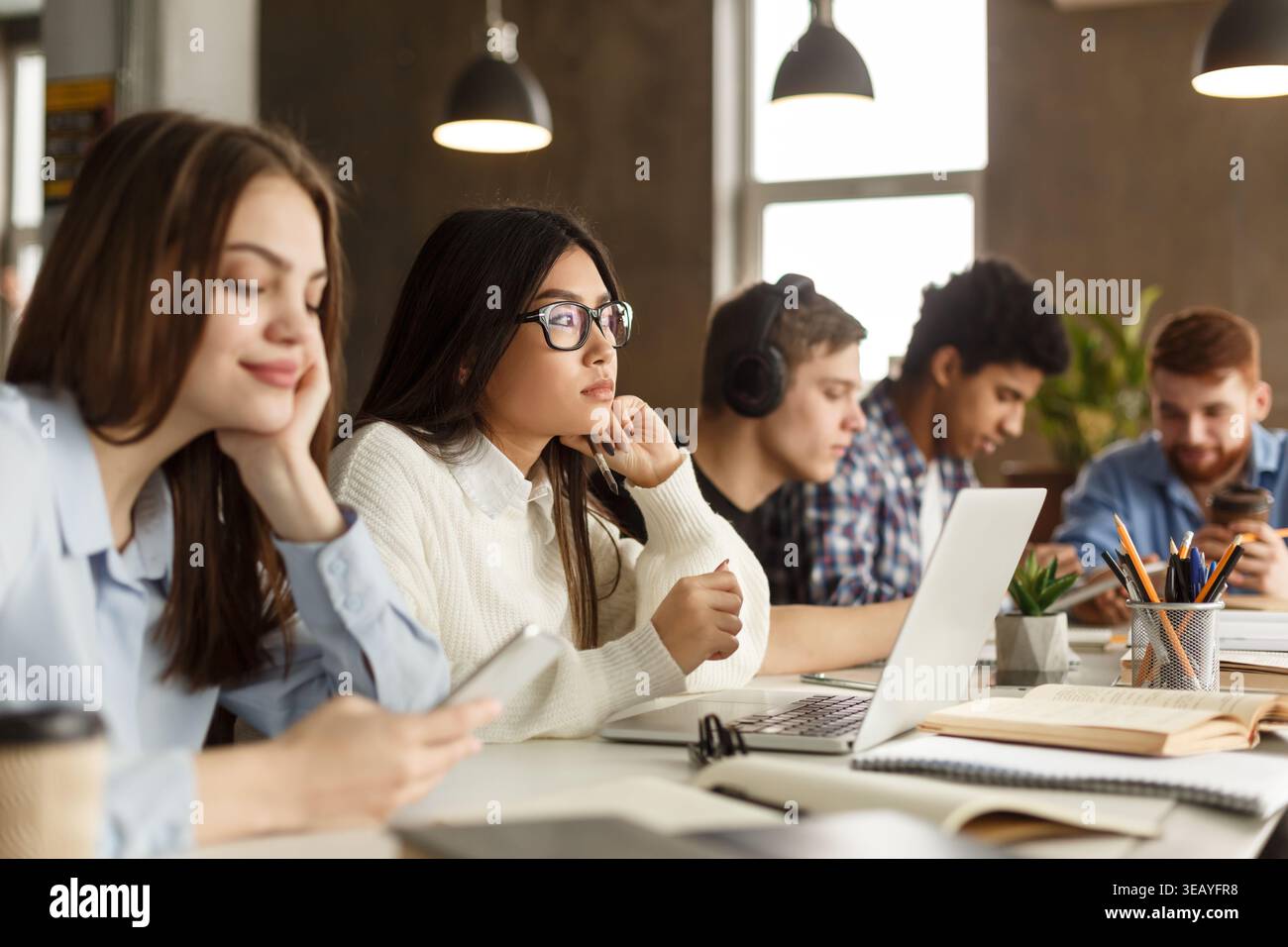 Students Engaged in Study Session at Modern Workspace During Afternoon Stock Photo