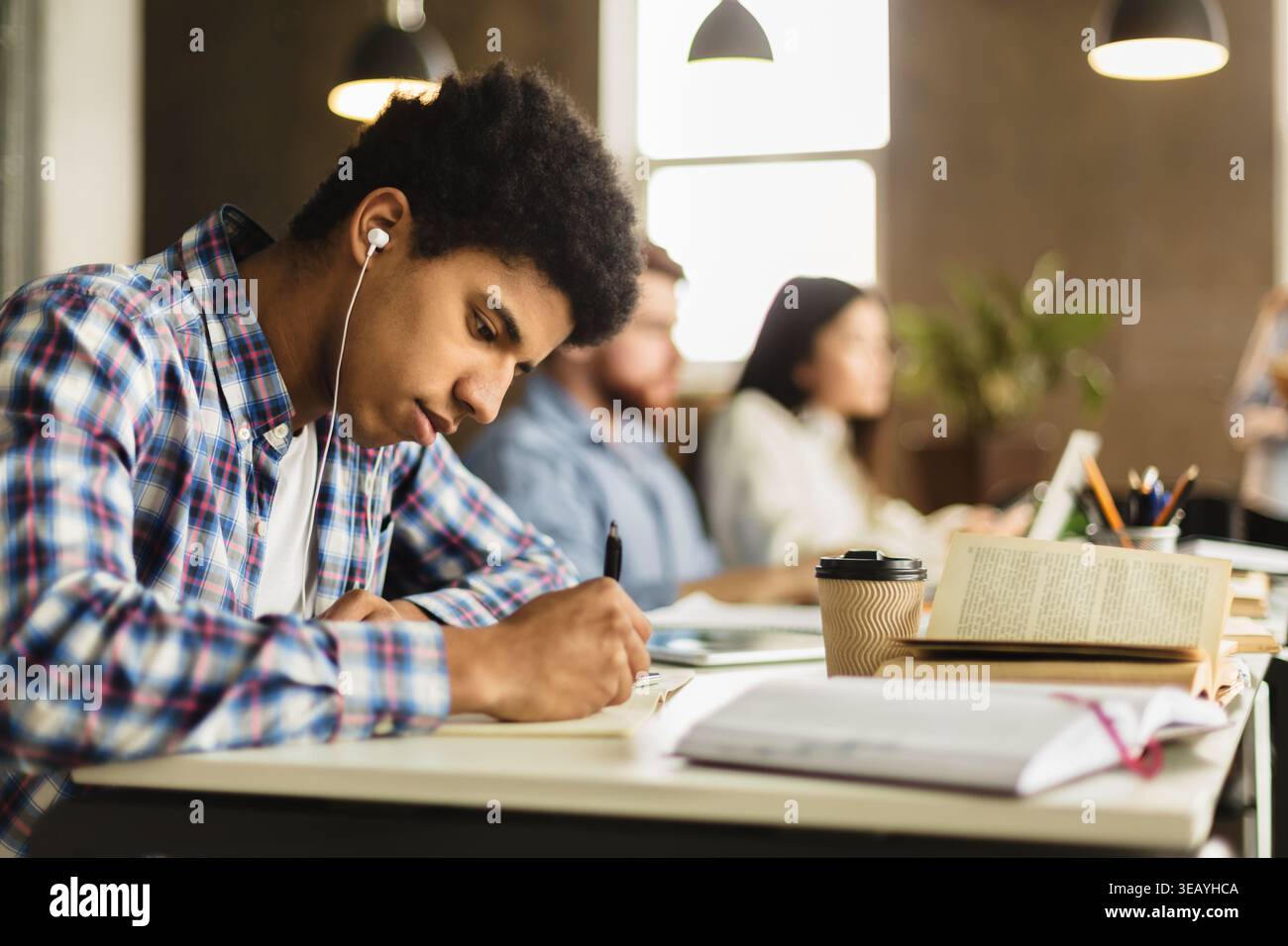 Black guy taking notes, preparing for classes in library Stock Photo