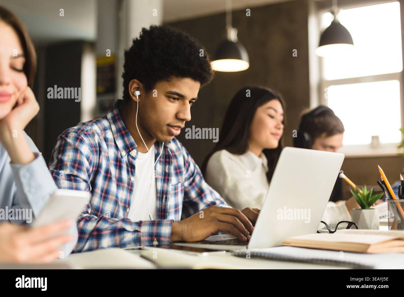Students Engaged in Study Session While Using Technology in Modern Workspace Stock Photo