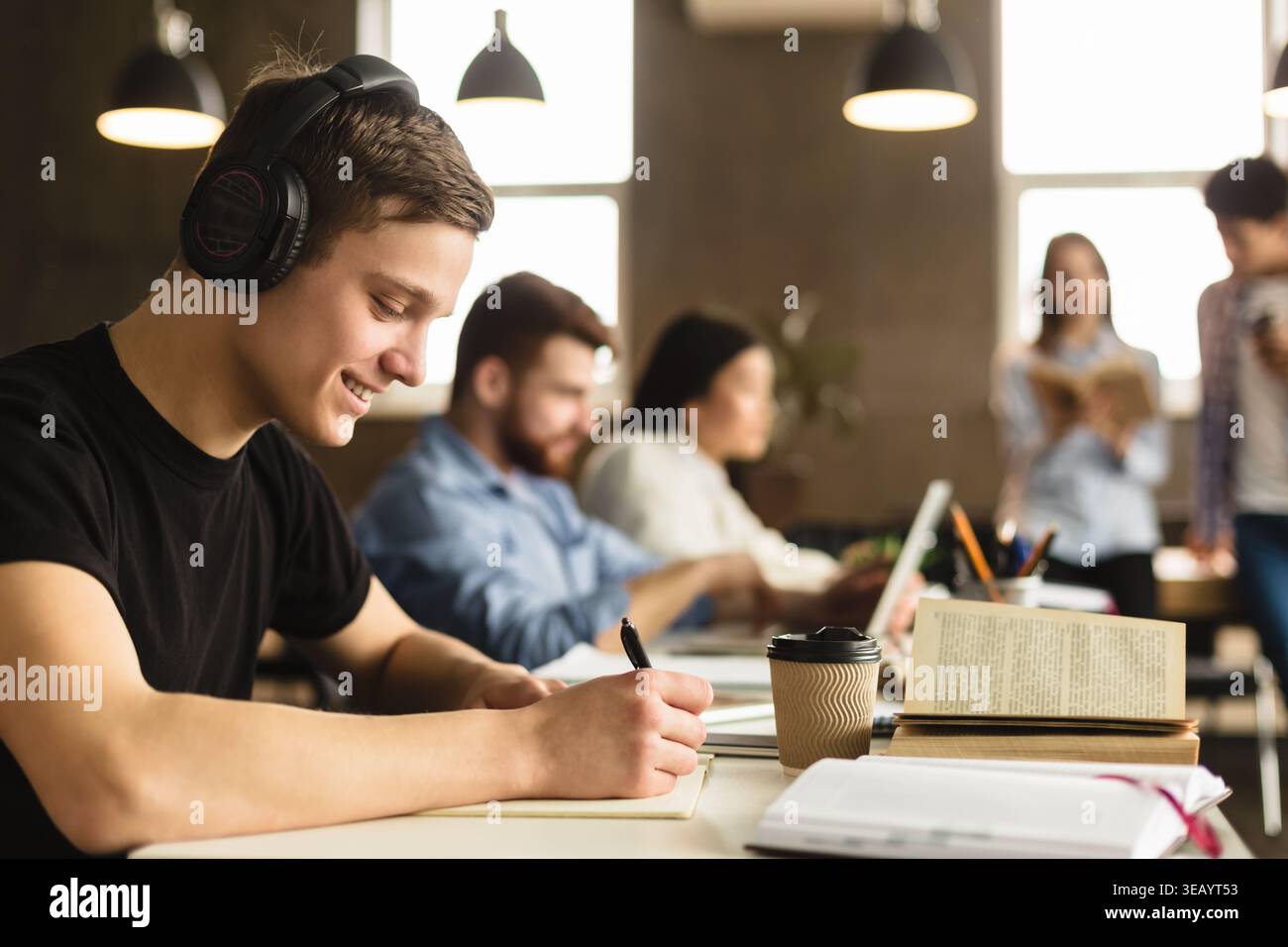 Student guy preparing for classes, taking notes in library Stock Photo