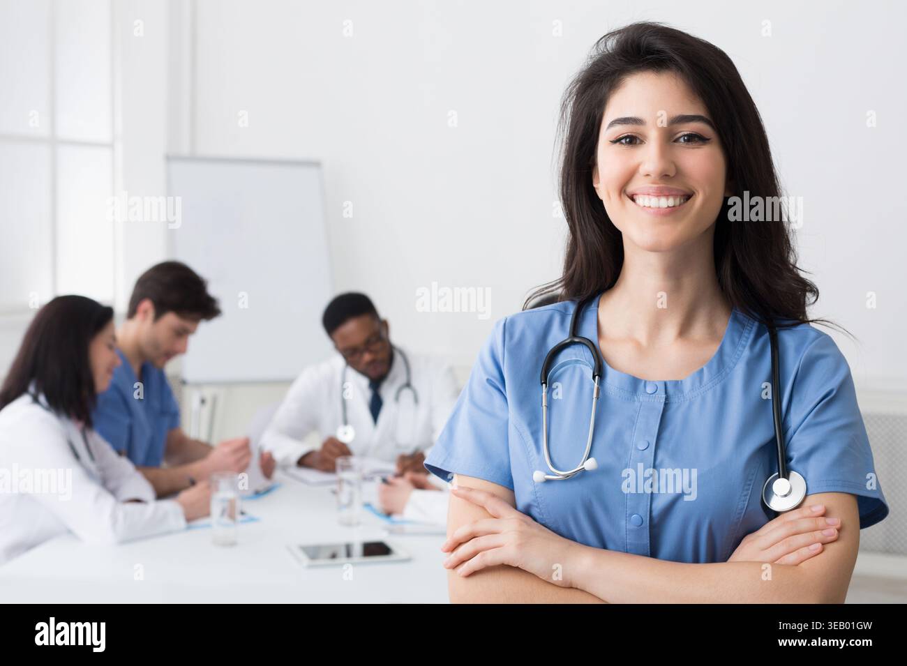 Happy Intern With Crossed Arms Looking At Camera During Conference Stock Photo