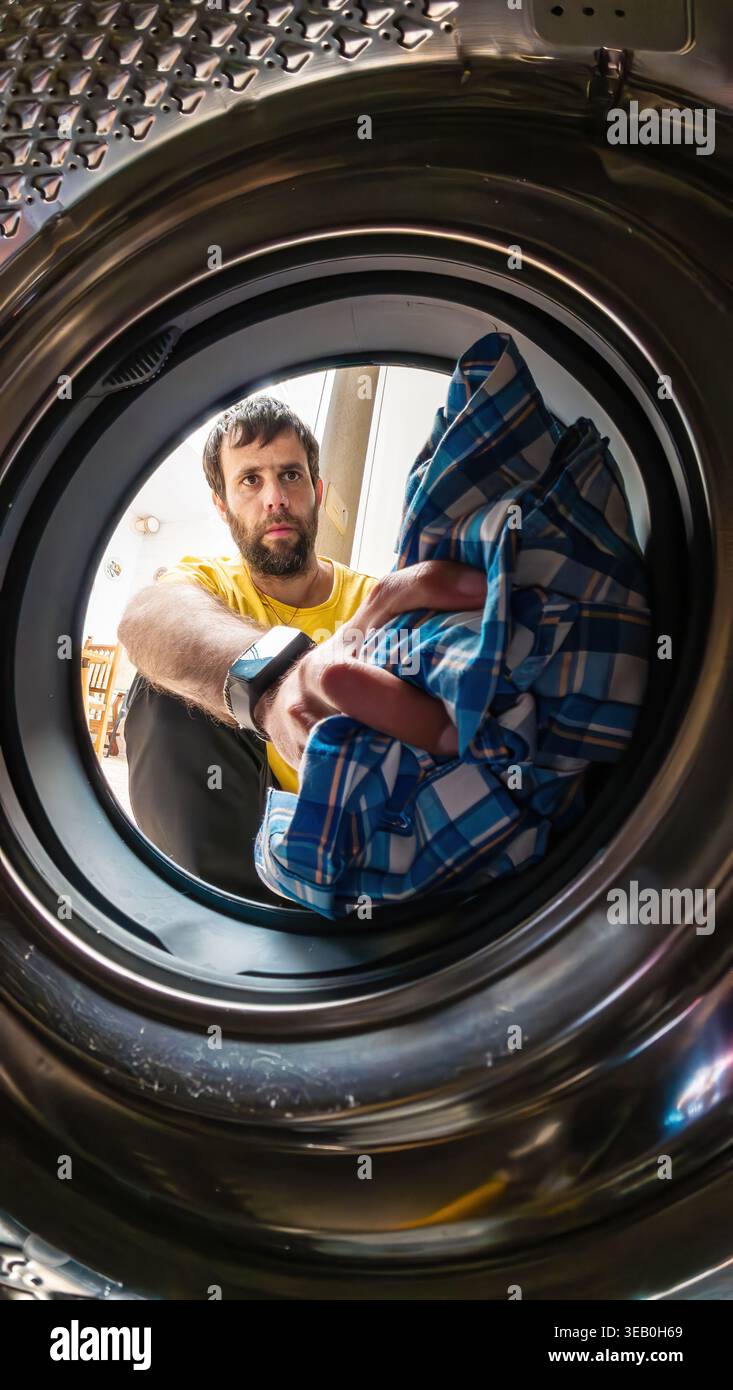 Man putting laundry into washing machine drum Stock Photo