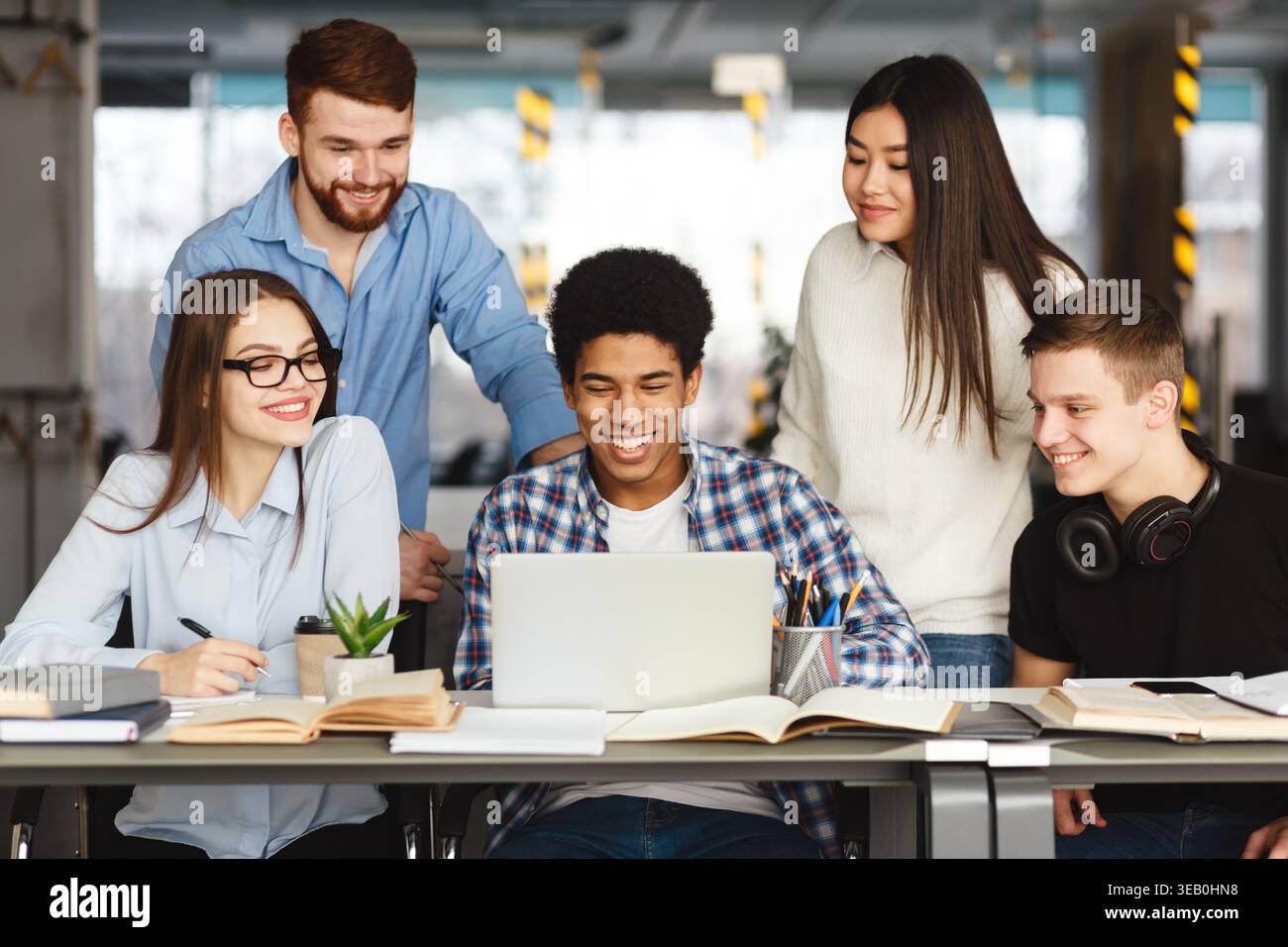 Group of Students Collaborating on a Laptop in a Modern Study Space Stock Photo