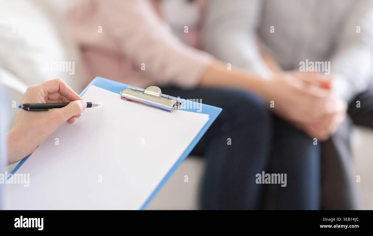 Psychotherapist writing in blank notepad at therapy session Stock Photo