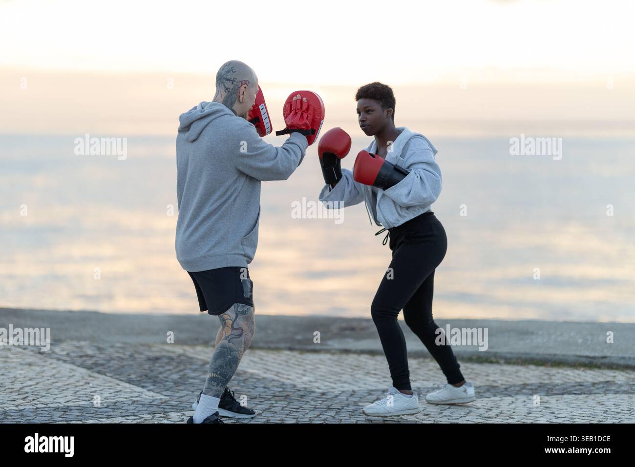 Woman practicing boxing punches with coach outdoors Stock Photo
