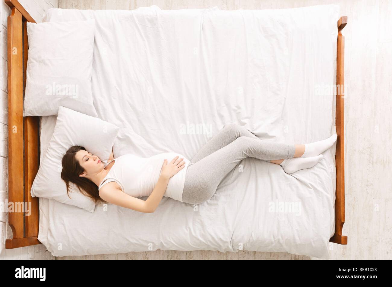 Woman Resting Comfortably on a Serene Bed in a Cozy Bedroom During the Morning Hours Stock Photo