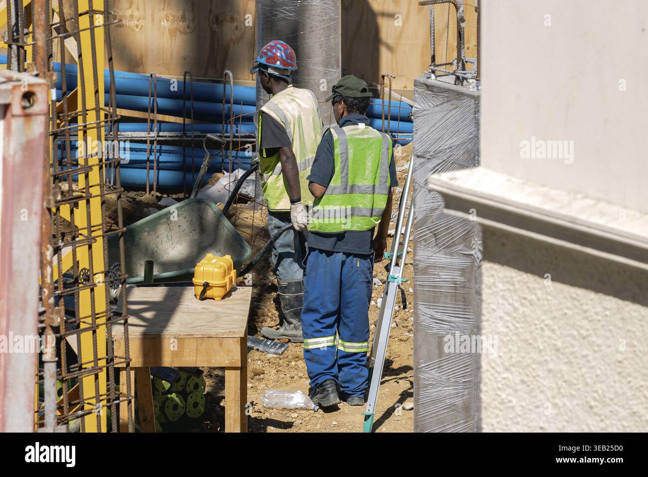 Two workers in uniform and reflective vest at a construction site Stock Photo