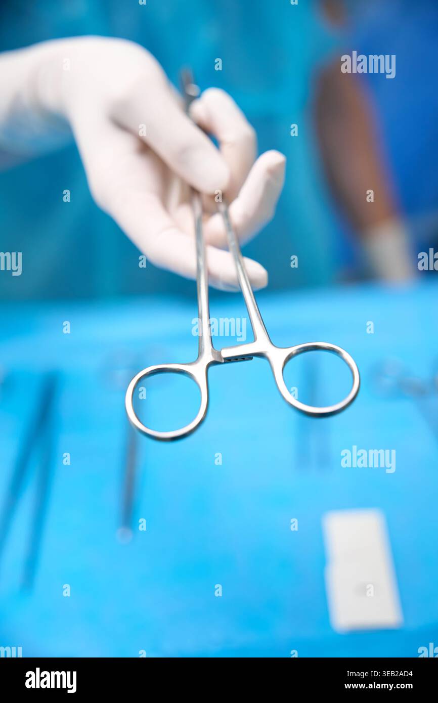Operating Human Using Razor Knife Human hand in white glove holding surgical forceps in operating room ...