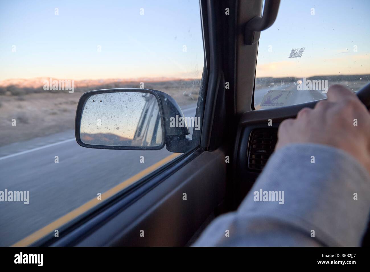 Driver's hands on steering wheel during desert road trip Stock Photo