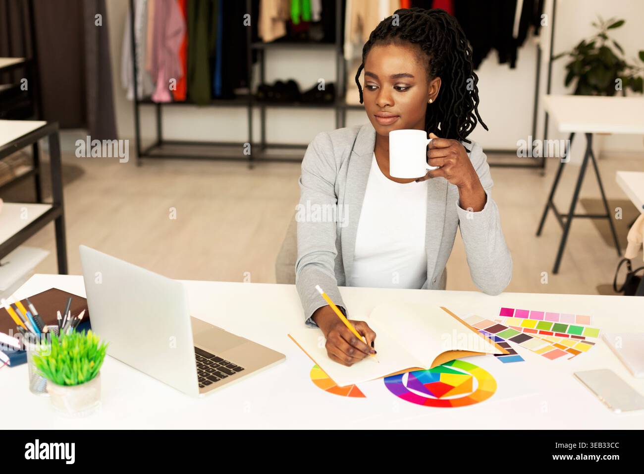 Creative Designer Working at a Modern Studio While Enjoying a Cup of Coffee Stock Photo