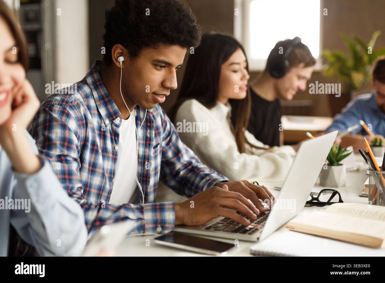 Student learning lessons in school library, using laptop Stock Photo