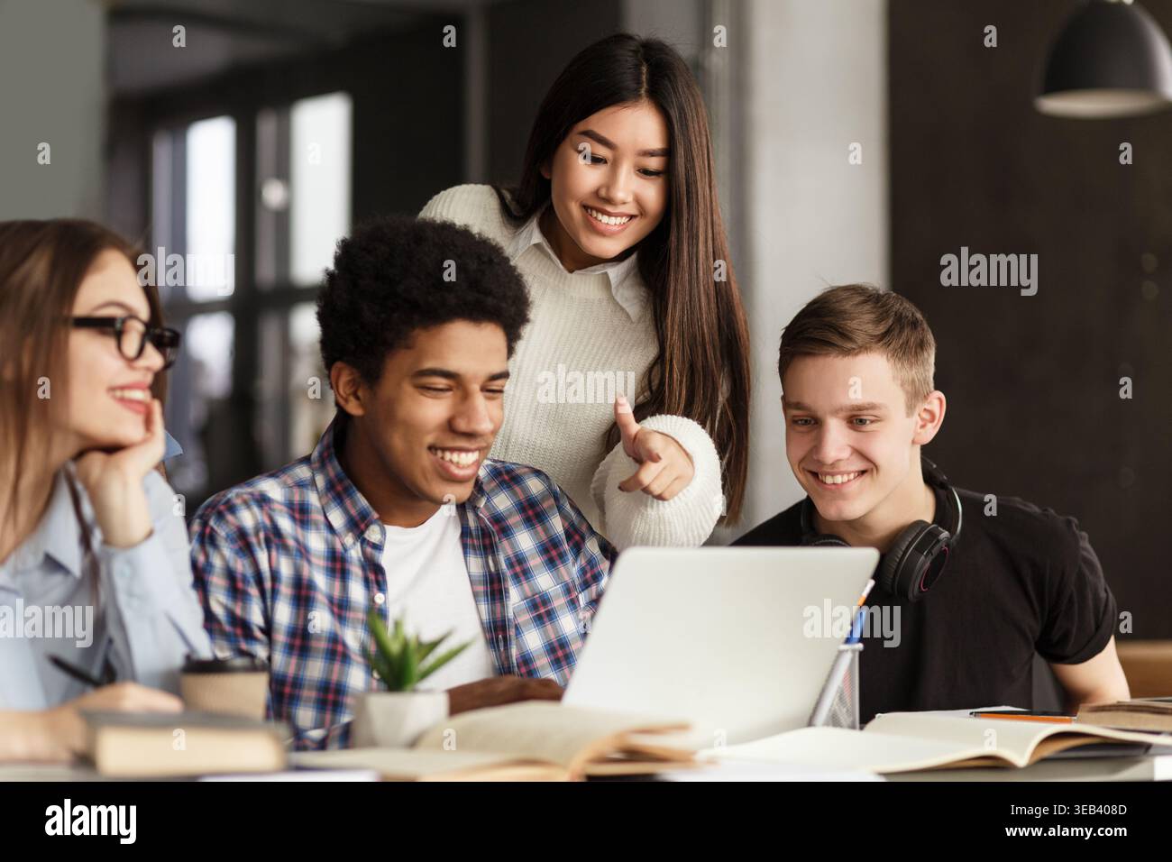 College students using laptop in library, studying together Stock Photo