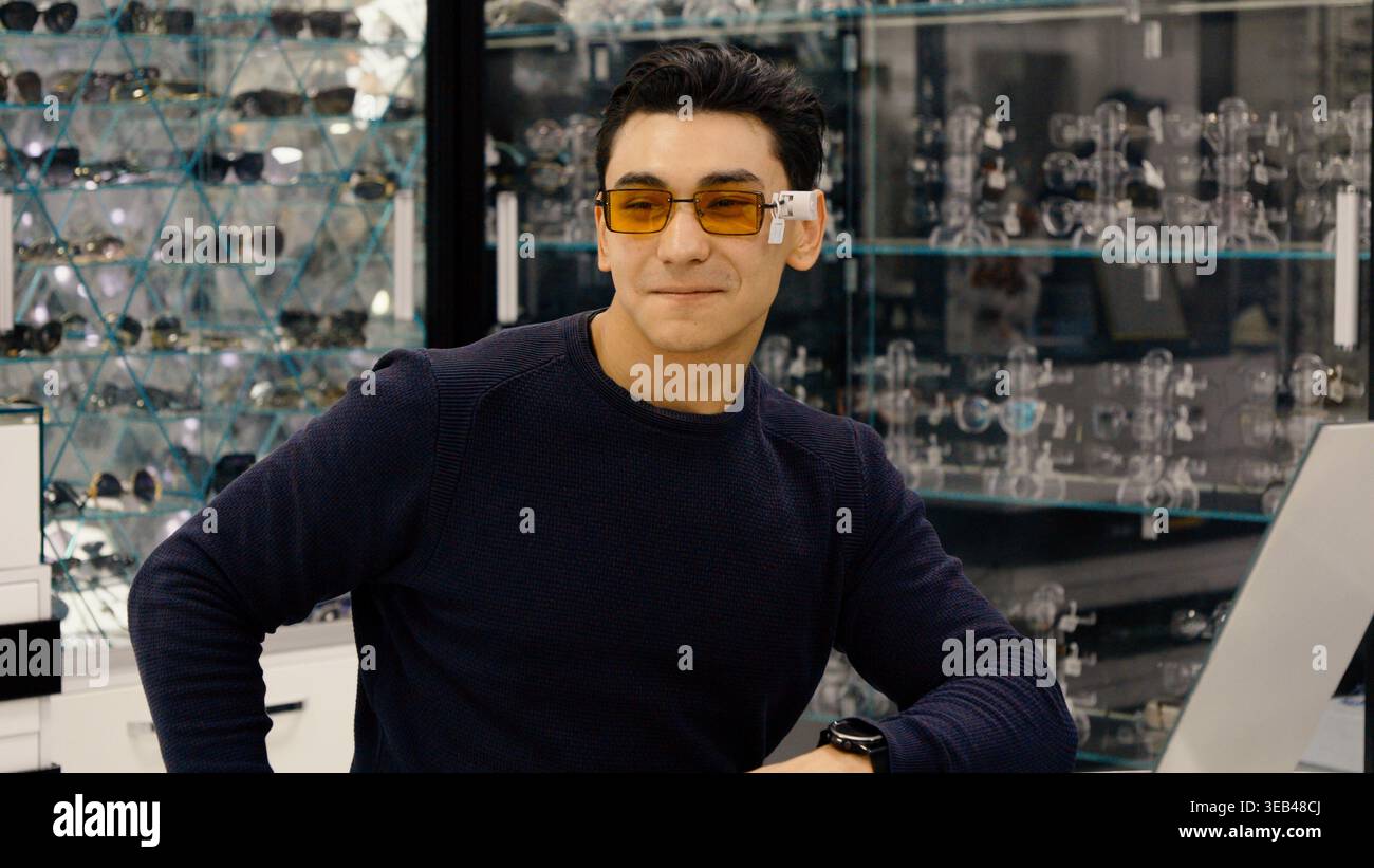 Stylish man wearing yellow sunglasses in optician shop Stock Photo