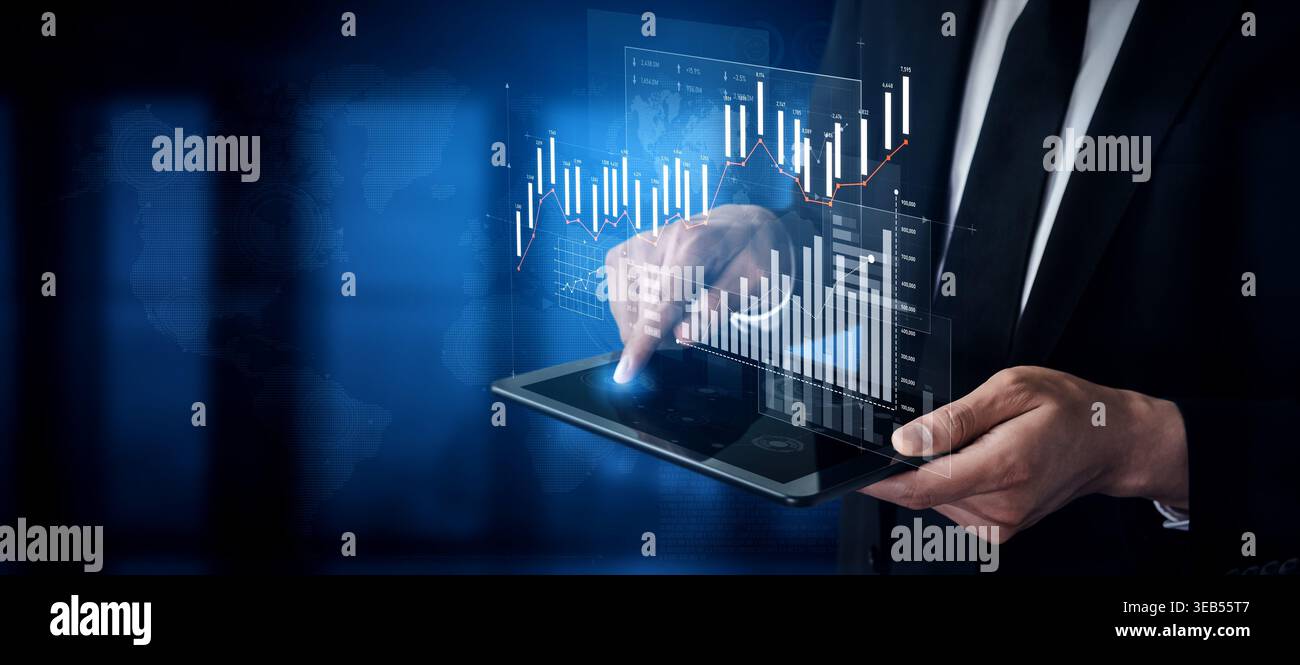 A professional man in a suit interacts with a tablet displaying holographic financial graphs and charts, representing modern business analytics and Stock Photo