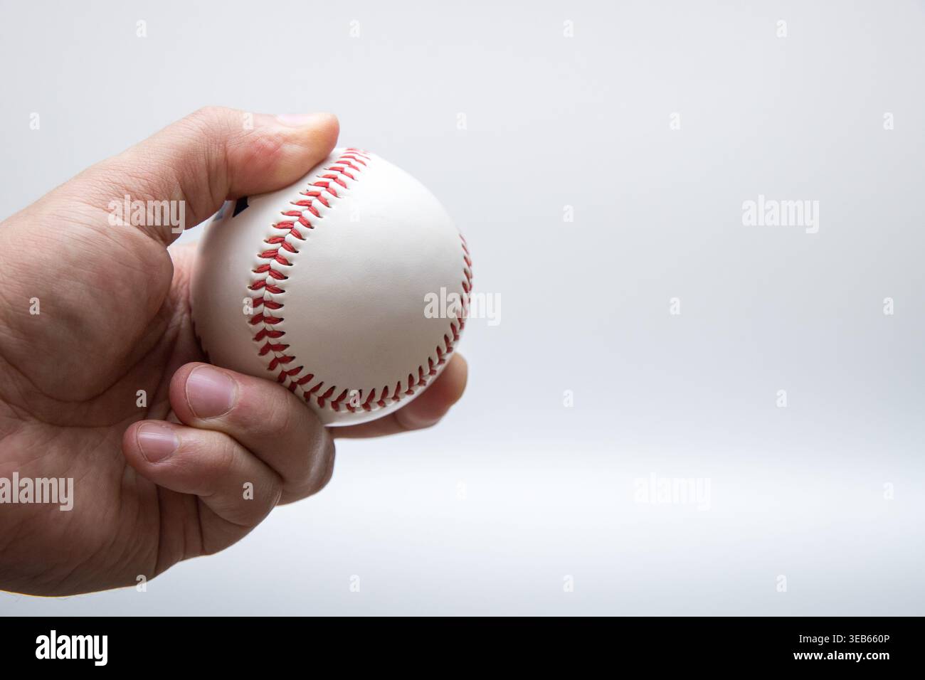 Hand holding baseball ball isolated on light background Stock Photo
