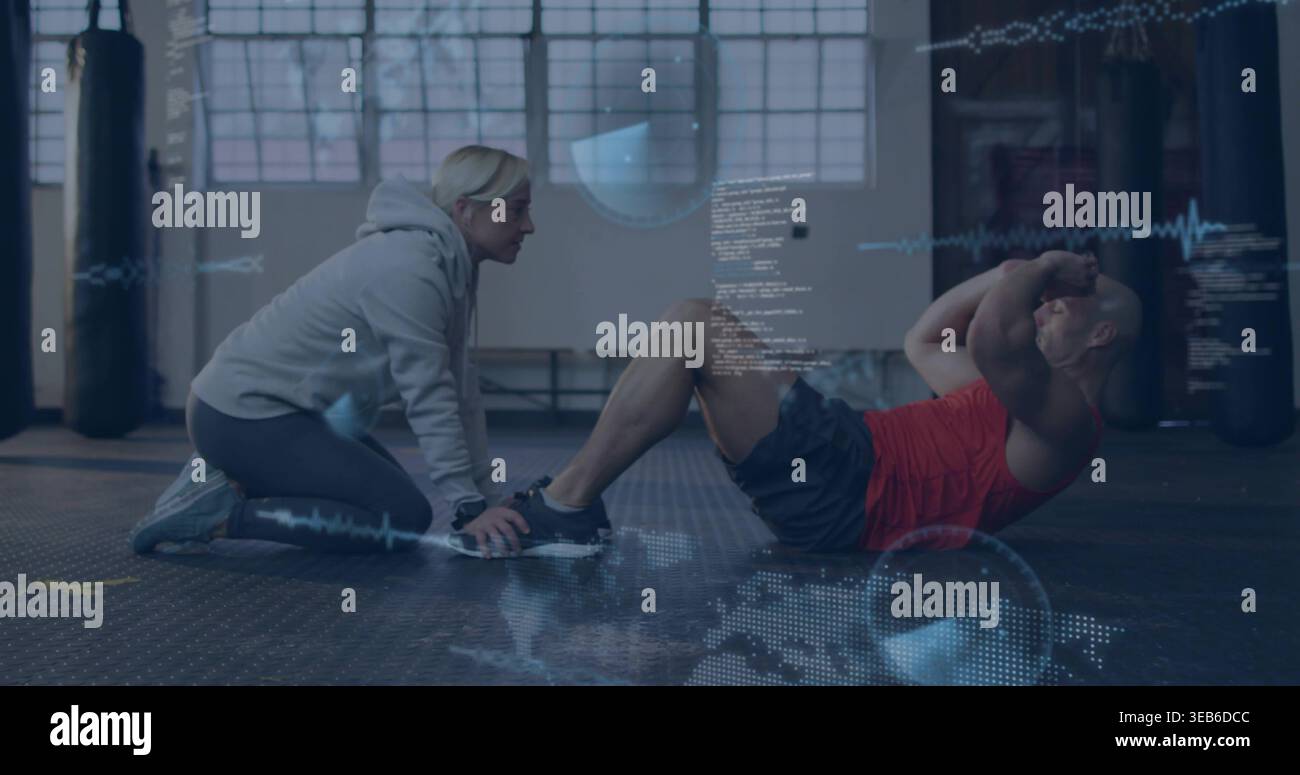Kneeling woman in gray hoodie holding trainee's feet, man in red-top doing sit-ups in gym, overlays Stock Photo