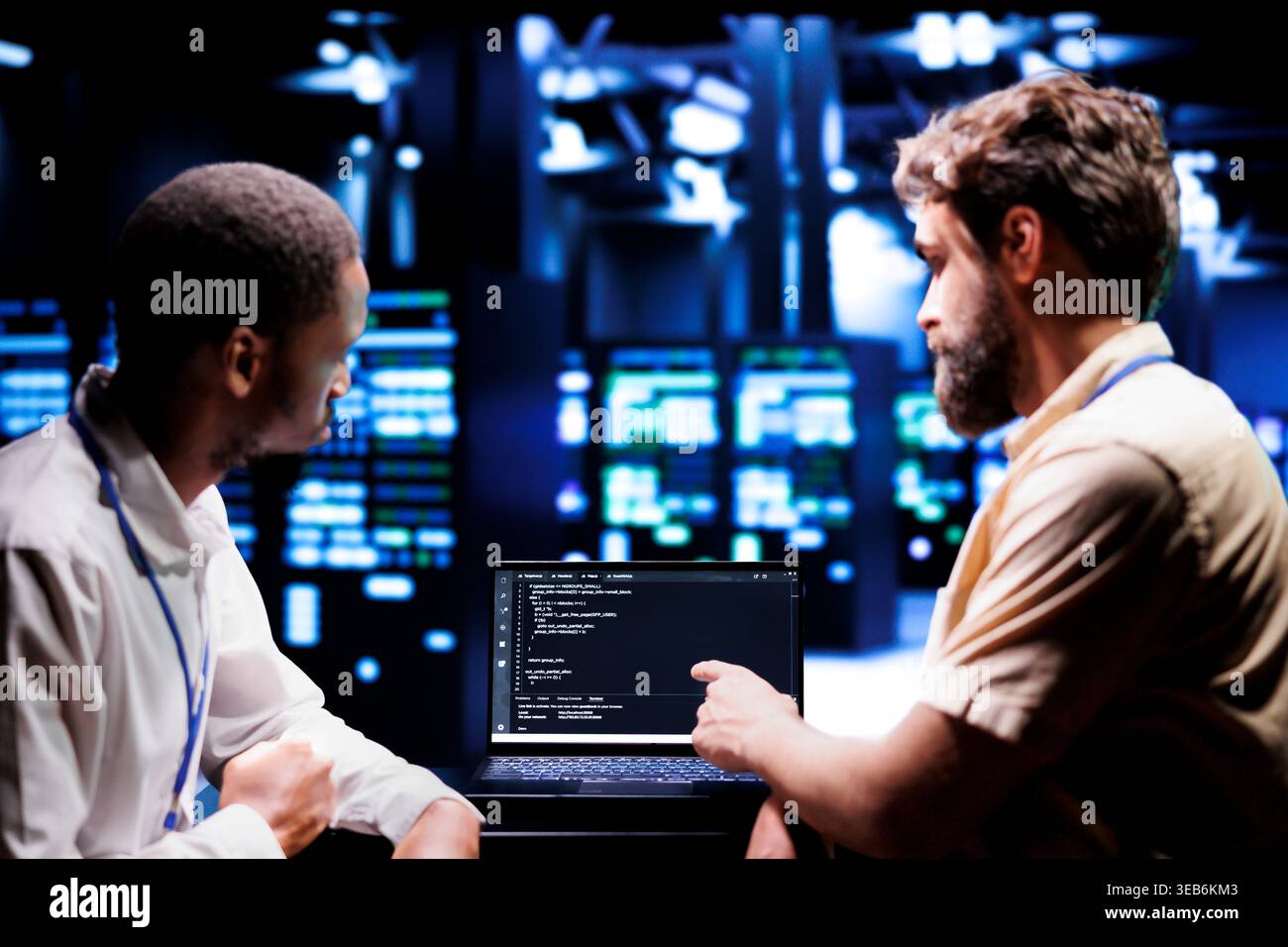 IT developers coworkers writing script code in server room on laptop terminal. Teamworking programmers doing maintenance work in technologically advanced data center updating racks software Stock Photo