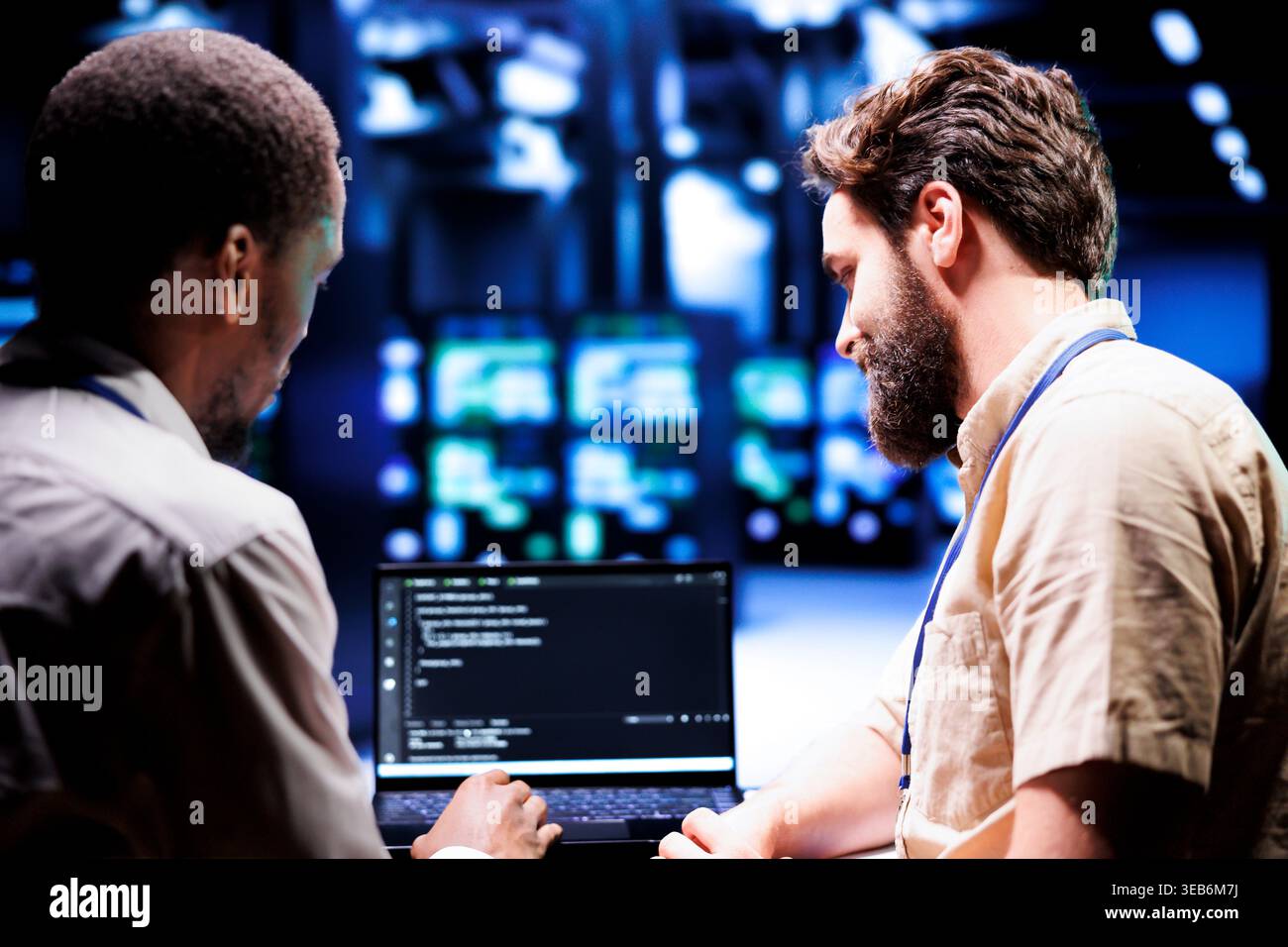 IT developers collaborating in server farm writing script code on laptop terminals. Programmers team conducting maintenance tasks in highly advanced data center, ensuring racks software is up to date Stock Photo