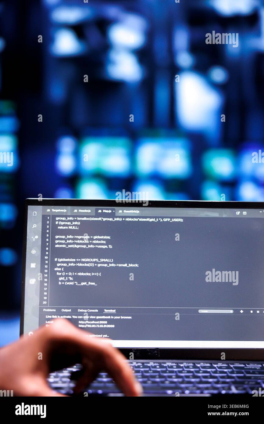 Computer scientists updating rackmounts, writing lines of code on laptop terminal, close up. Employees using JavaScript, Java, and database programming to ensure seamless server farm computing Stock Photo