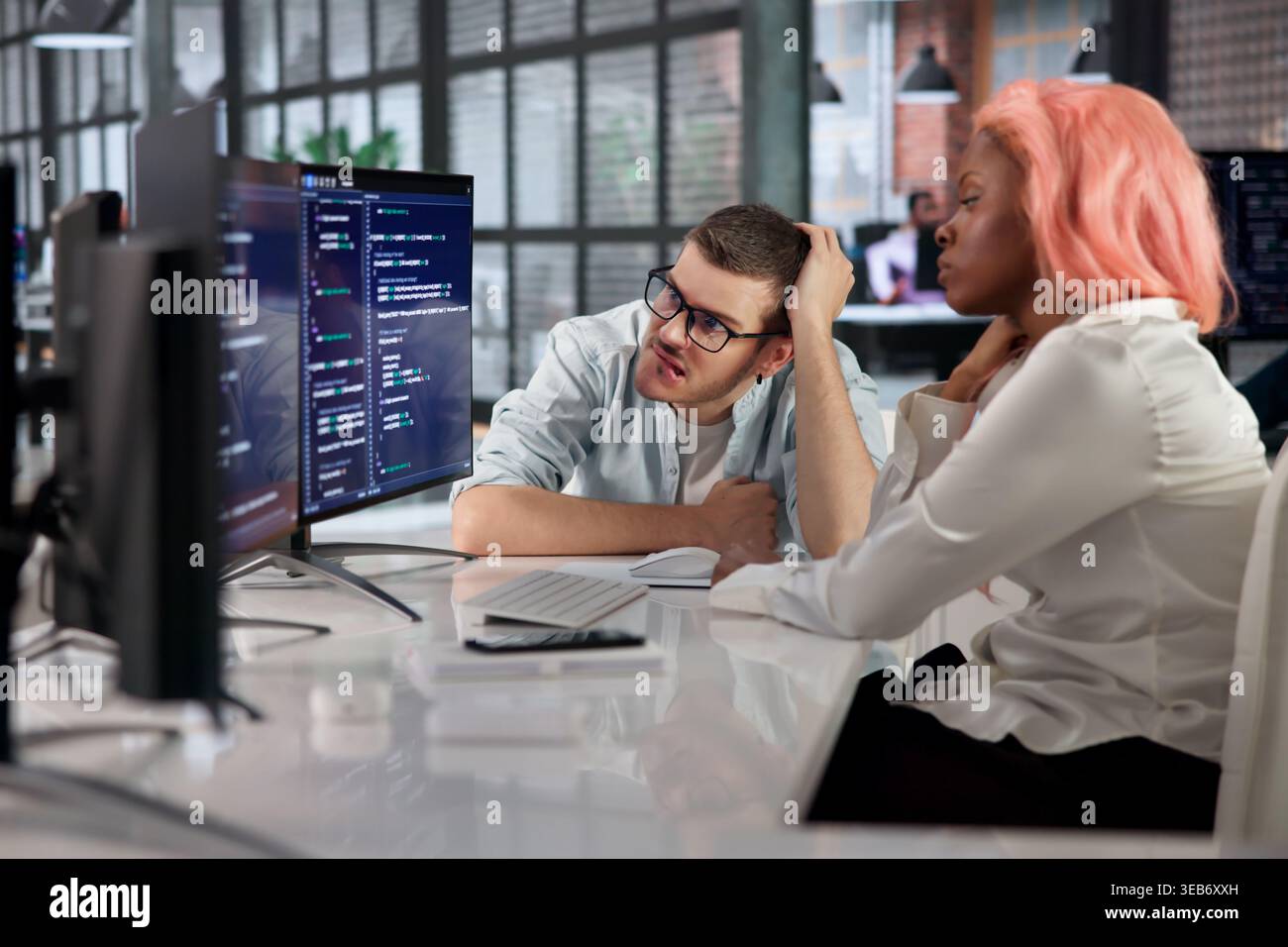 Software Engineer Quietly Fixes Broken Code While Stressed At Busy Desk. Stock Photo